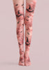 A pair of sheer pink tights with a Halloween-themed print featuring black witch hats, bats, and pumpkins, shown on a model's legs against a solid pale pink background.